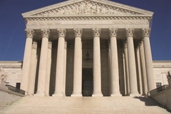 [ai] The front view of a large neoclassical building with six prominent columns and a triangular pediment, leading up to a set of steps under a clear blue sky.